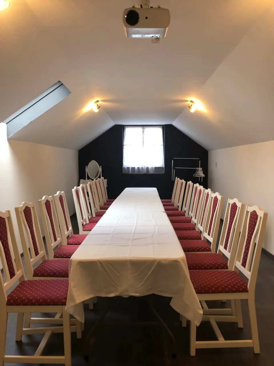 A galériás konferenciaterem hosszú asztallal és projektorral